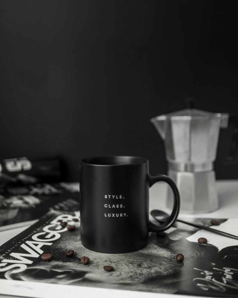 Black coffee mug with a luxury feel, surrounded by coffee beans and a moka pot.